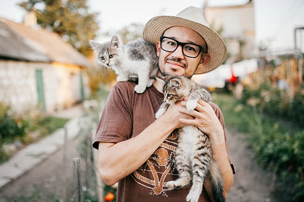 Happy Young Man Holding Two Little Kittens Hands